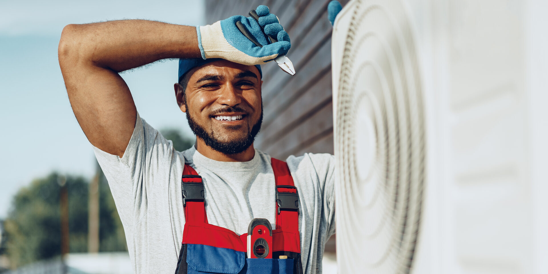 Smiling HVAC technician working on an outdoor air conditioning unit