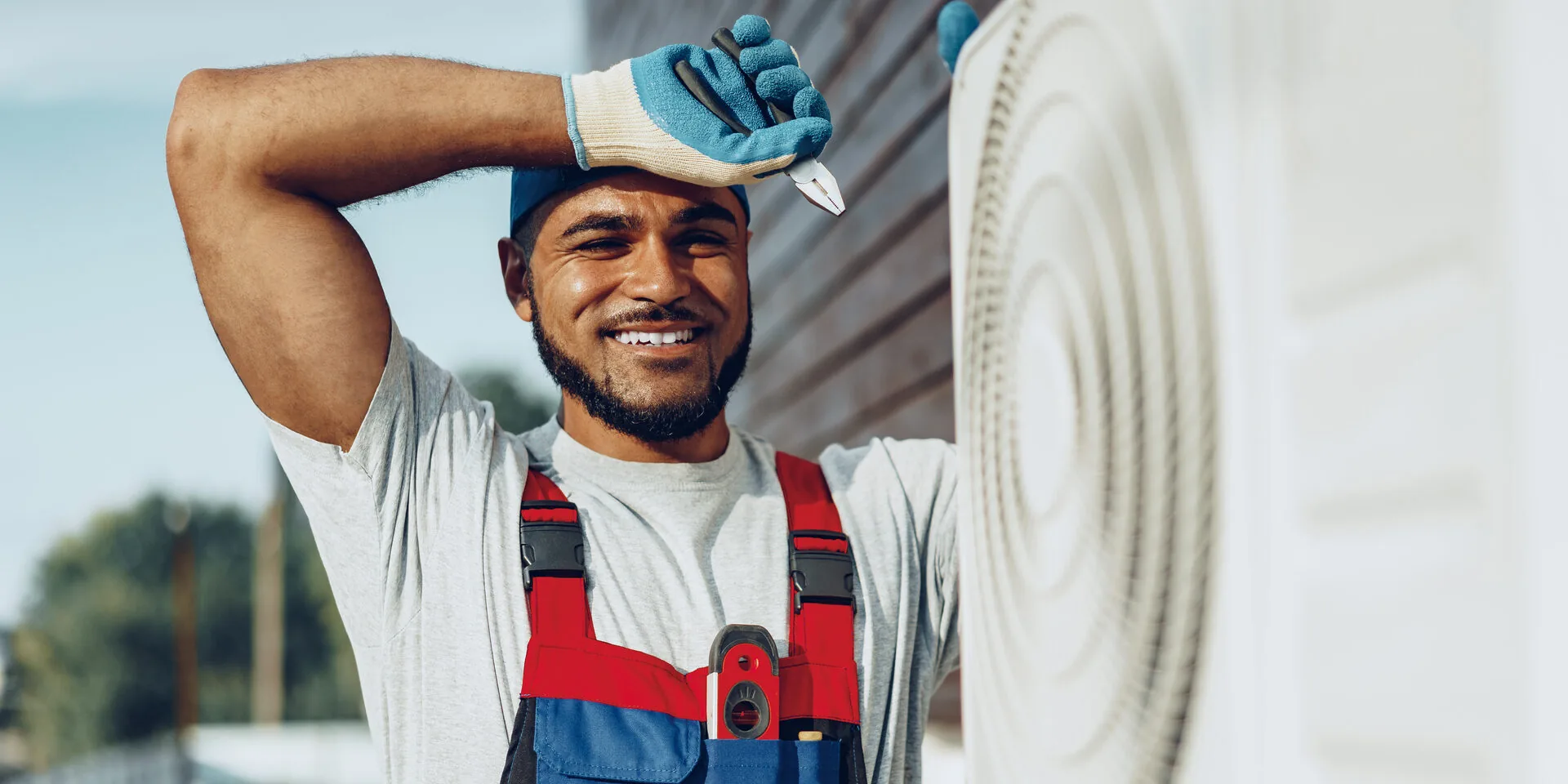 Smiling HVAC technician working on an outdoor air conditioning unit